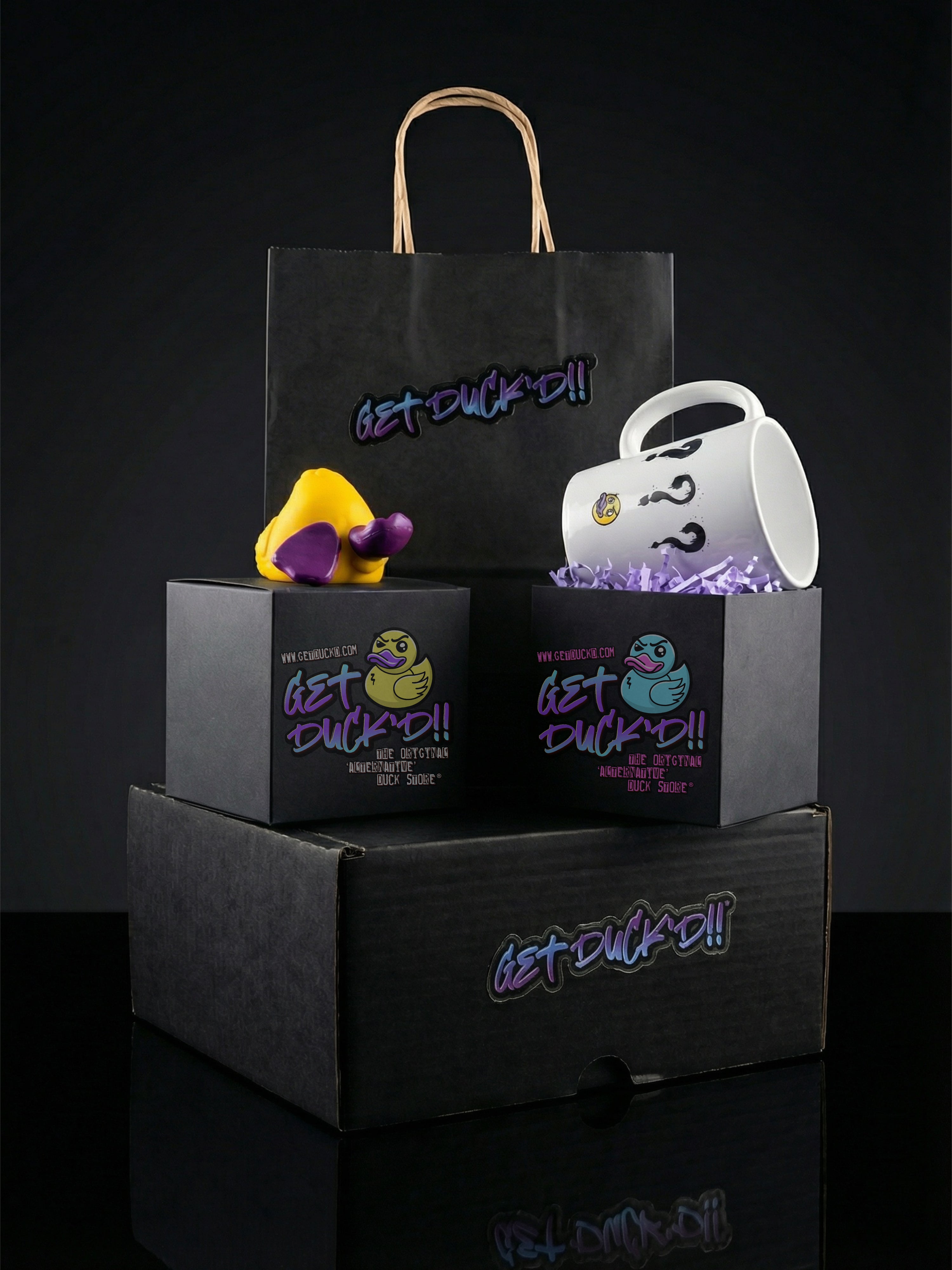Product set with a mug, rubber duck, and premium packaging featuring 'Get Duckd!' branding on a dark background.